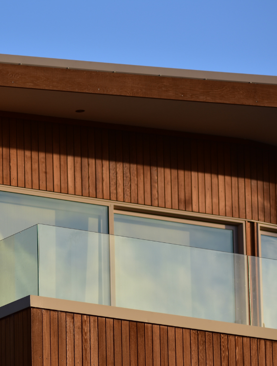 Houten buitengevel van een huis met balkon uit glas