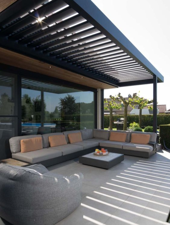 Een terras, grenzend aan een huis, met een lounge voor buiten en zonnewering in het zwart