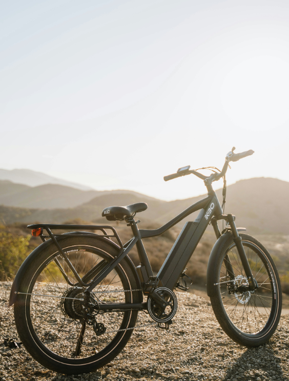 Zwarte elektrische fiets op een heuvel met uitzicht over andere heuvels en stralend zonlicht
