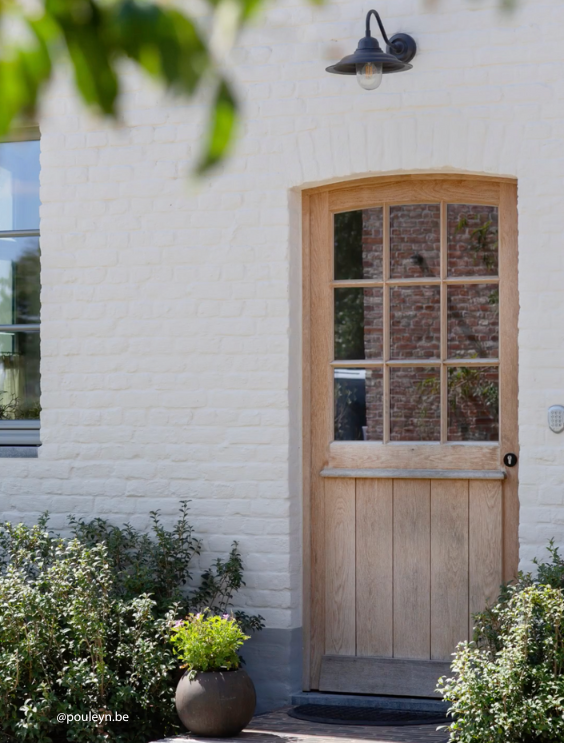Landelijke houten achterdeur met plantjes en witte gevel